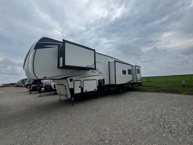 A large white trailer is parked in a gravel lot.