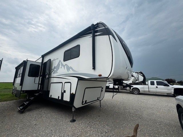 A white rv is parked in a gravel lot next to a truck.