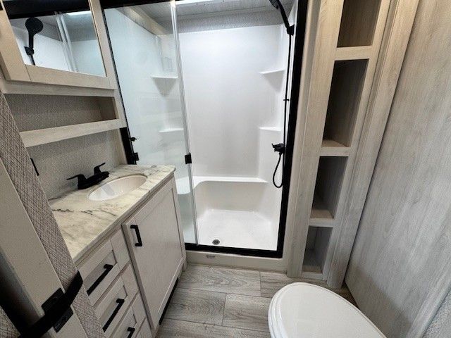 A bathroom with a toilet a sink and a shower.