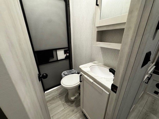 A bathroom with a toilet , sink and shower.