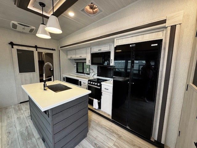 A kitchen with a large island , stove , refrigerator and sink.