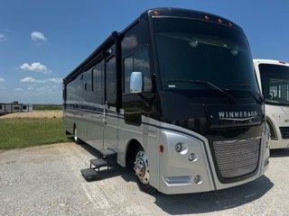 A large silver and black rv is parked in a parking lot.