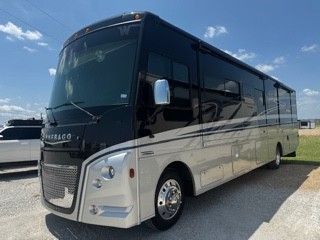 A large black and silver rv is parked in a parking lot.