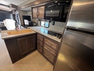 A kitchen in a rv with stainless steel appliances and wooden cabinets.
