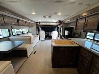 The inside of a rv with a kitchen , dining room , and living room.