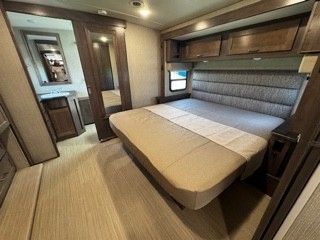 A bedroom in a rv with a bed and a bathroom.