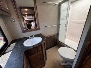 A bathroom in a rv with a sink , toilet and shower.