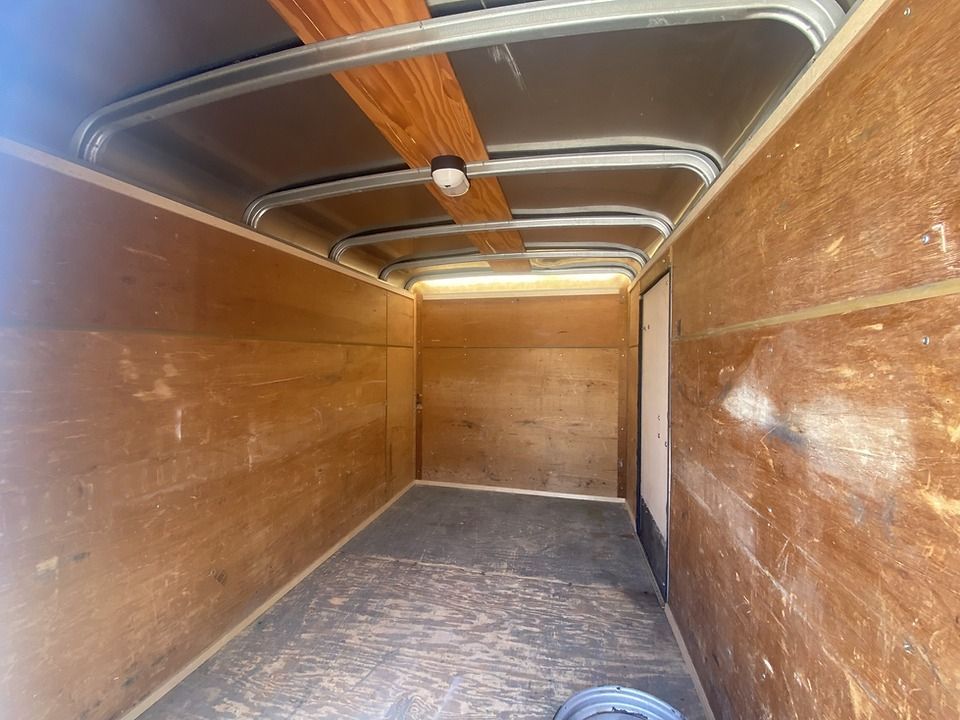 The inside of an empty trailer with wooden walls and a metal roof.
