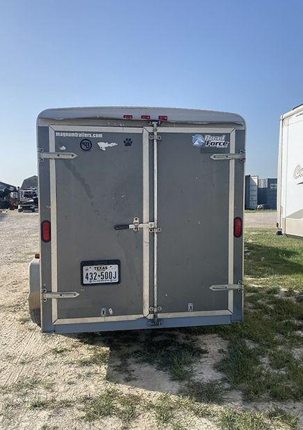 A gray trailer is parked in a grassy field.