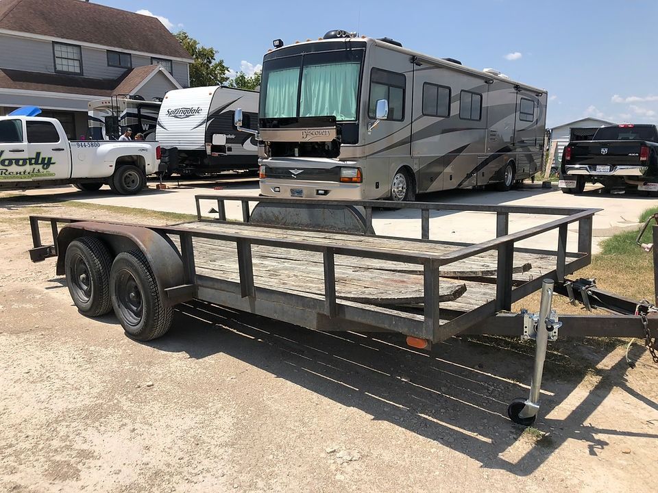 A trailer is parked next to a rv in a parking lot.