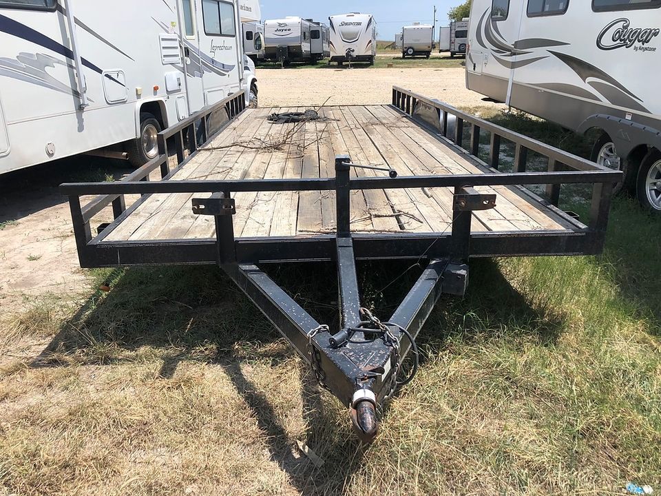 A trailer is parked in a grassy field next to a row of rvs.