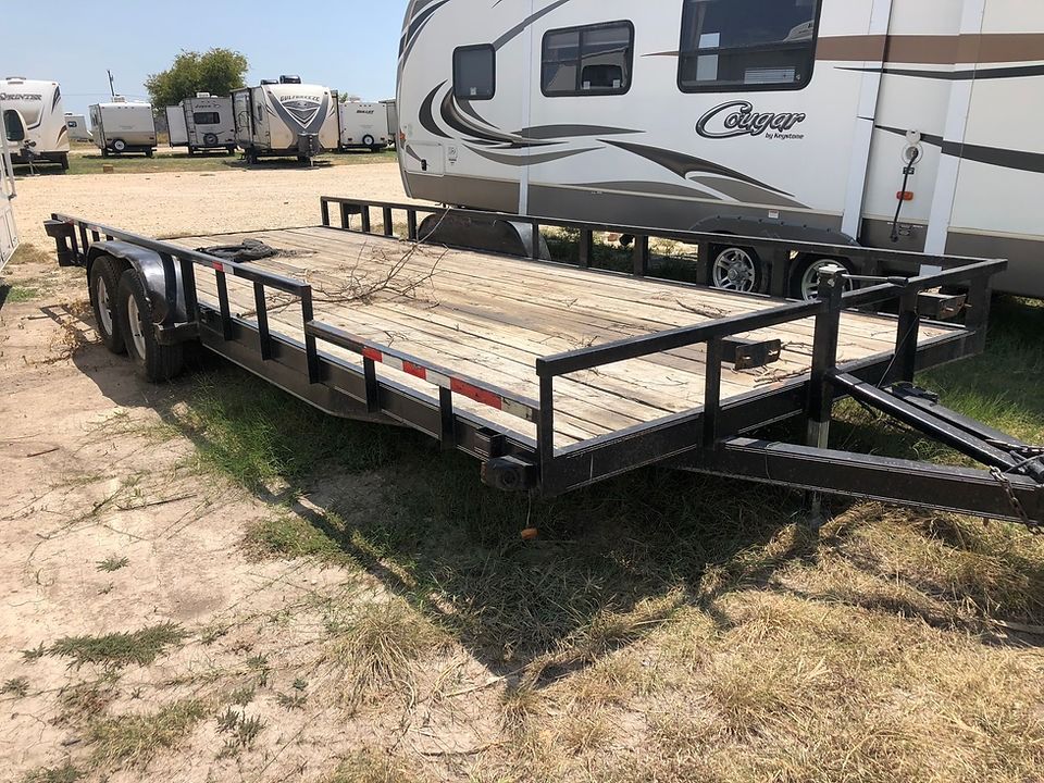 A trailer is parked in a grassy field next to a rv.