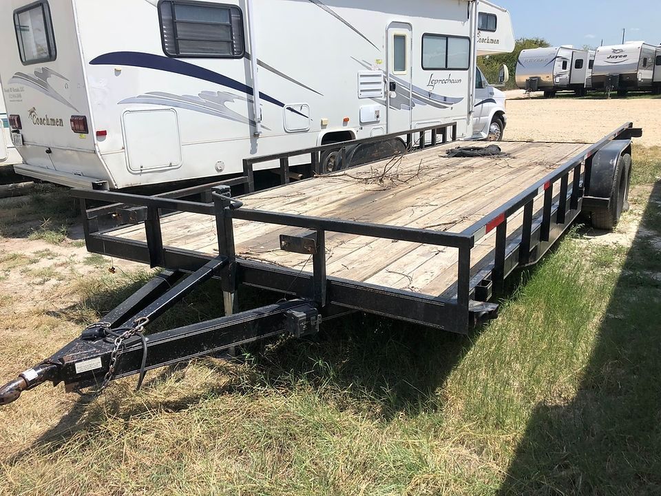 A trailer is parked in a grassy field next to a rv.