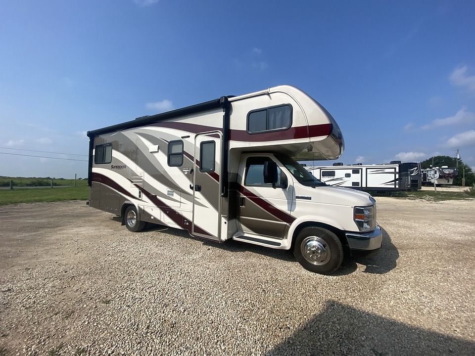 A white and brown rv is parked in a gravel lot.
