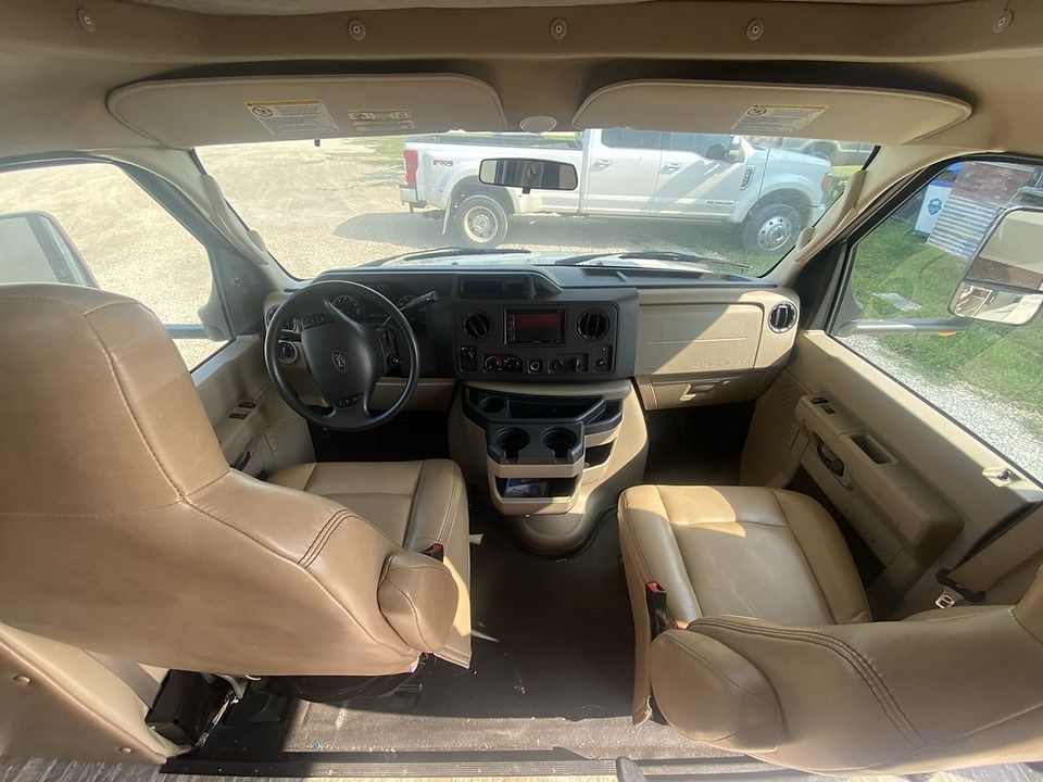 The interior of a rv with two seats and a steering wheel.