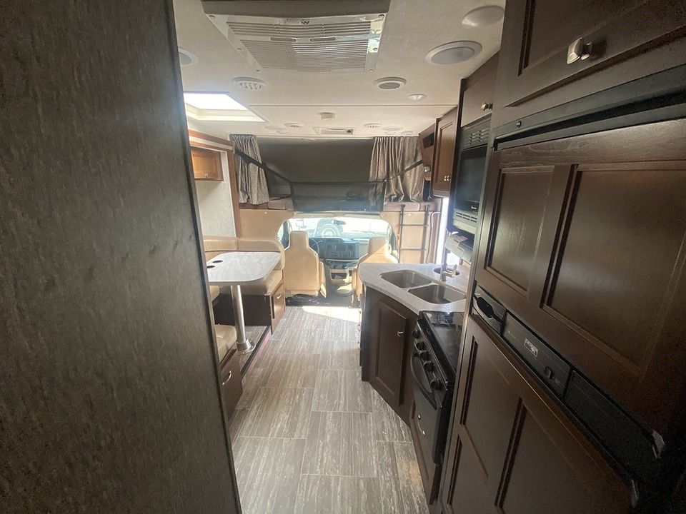 The inside of a rv with a table , sink , and microwave.