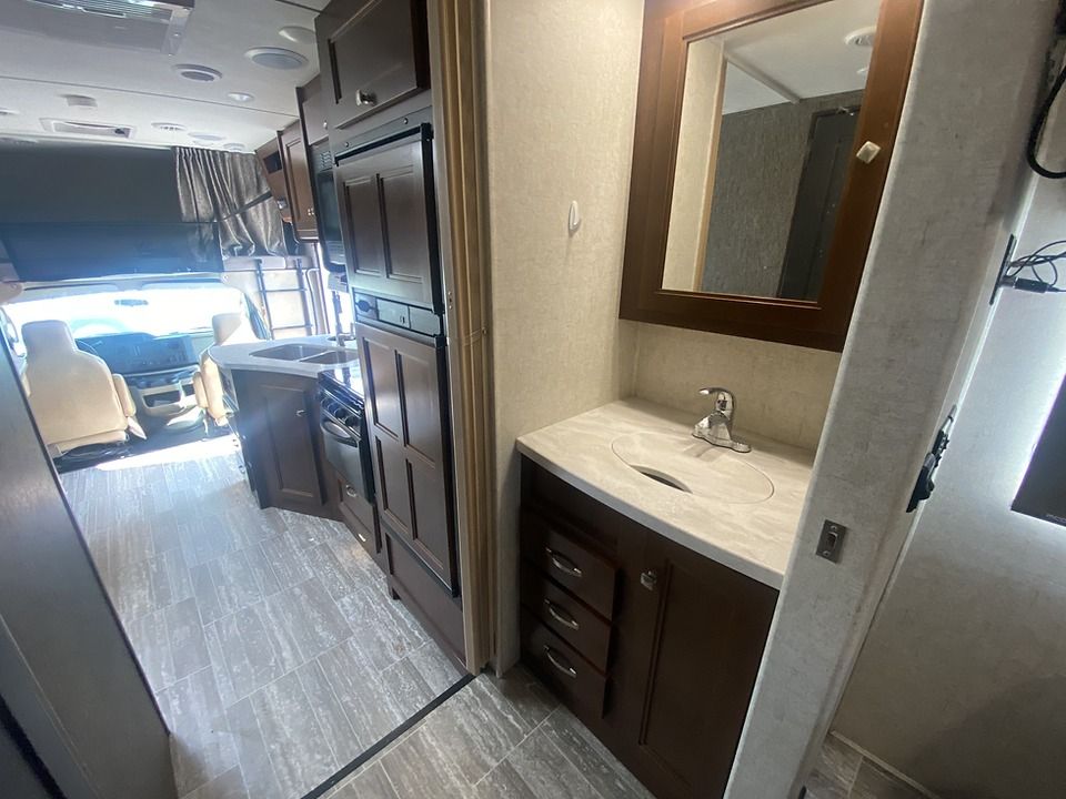 A bathroom in a rv with a sink and mirror.