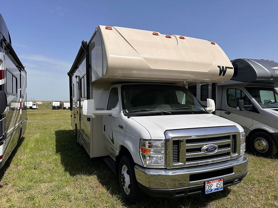 A white rv is parked in a grassy field.