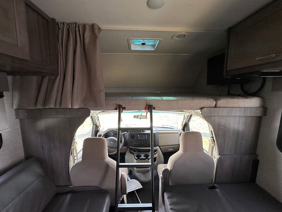 The inside of a rv with a bunk bed and a ladder.