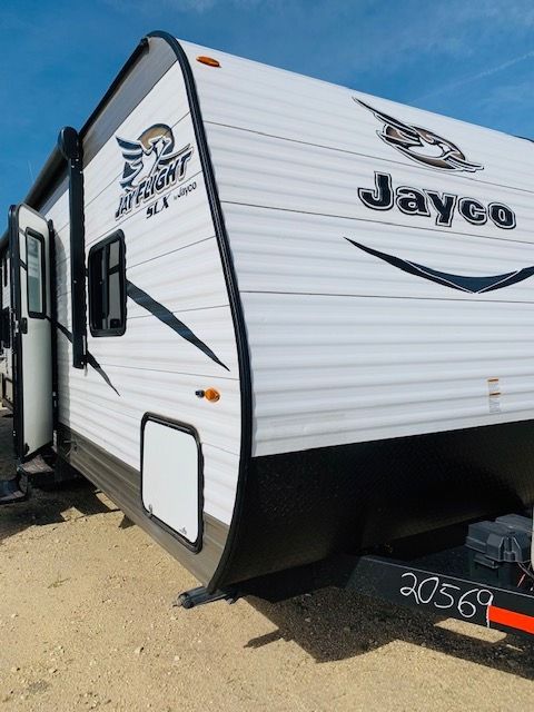 A white jayco trailer is parked in the dirt
