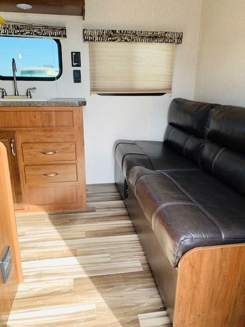 A living room with a couch , sink , and window.