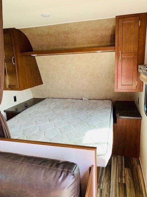 A bedroom in a trailer with a mattress and a couch.