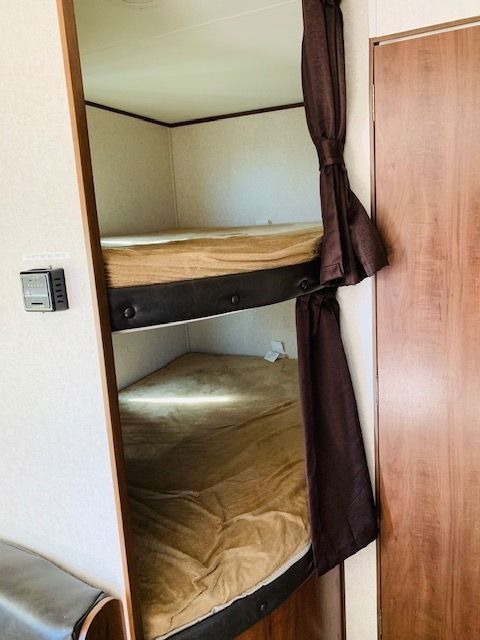 A bunk bed with a brown curtain behind it