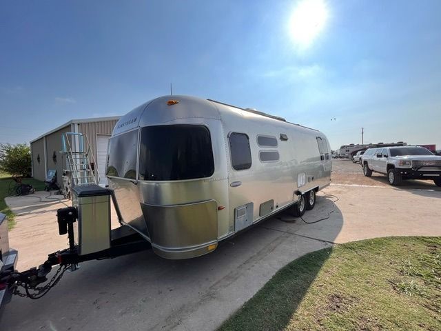A silver airstream trailer is parked on the side of the road.