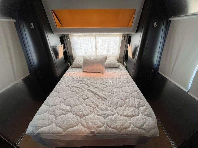 A bed with a mattress and pillows in a trailer.