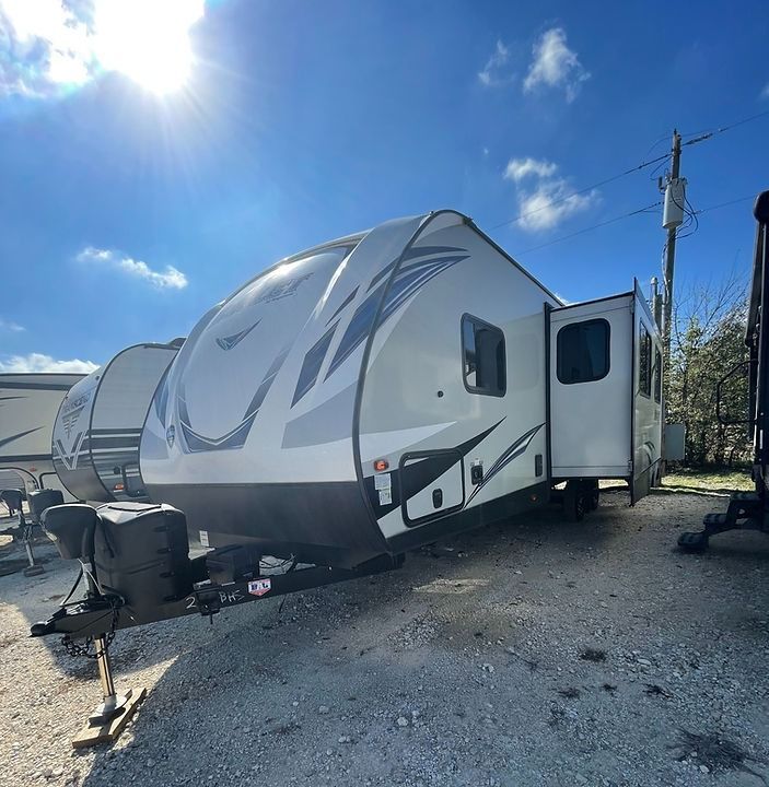 A white trailer is parked in a gravel lot.