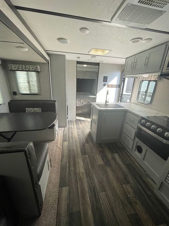 The inside of a rv with a stove , sink , and table.