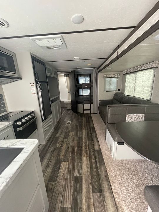 The inside of a rv with a kitchen , dining room , and living room.