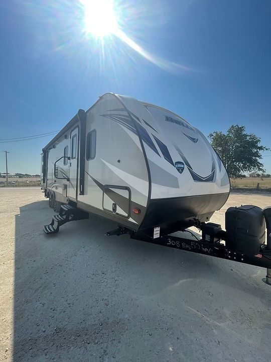 A white and black rv is parked in a parking lot.