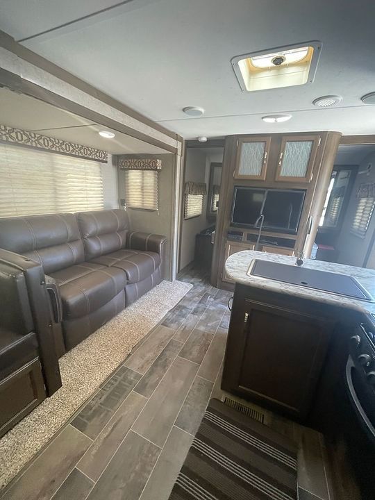 A living room in a rv with a couch and a kitchen.