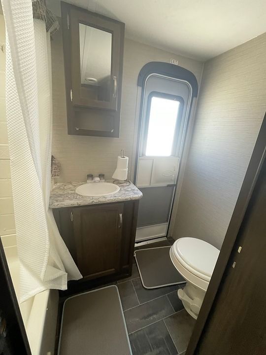 A bathroom with a toilet , sink and mirror