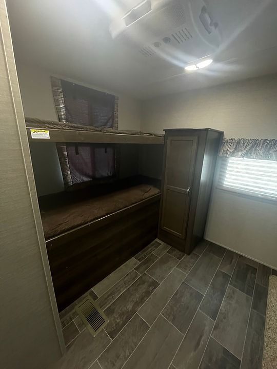 A room with bunk beds , a closet , and a window.