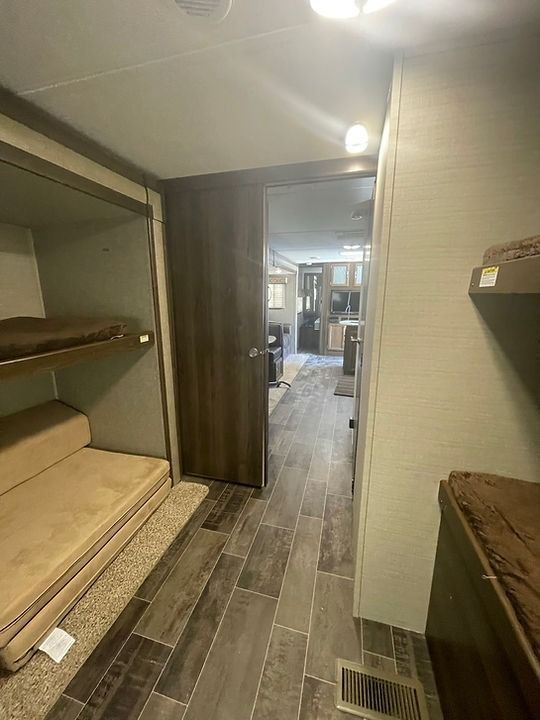 A hallway in a rv with bunk beds and a couch.