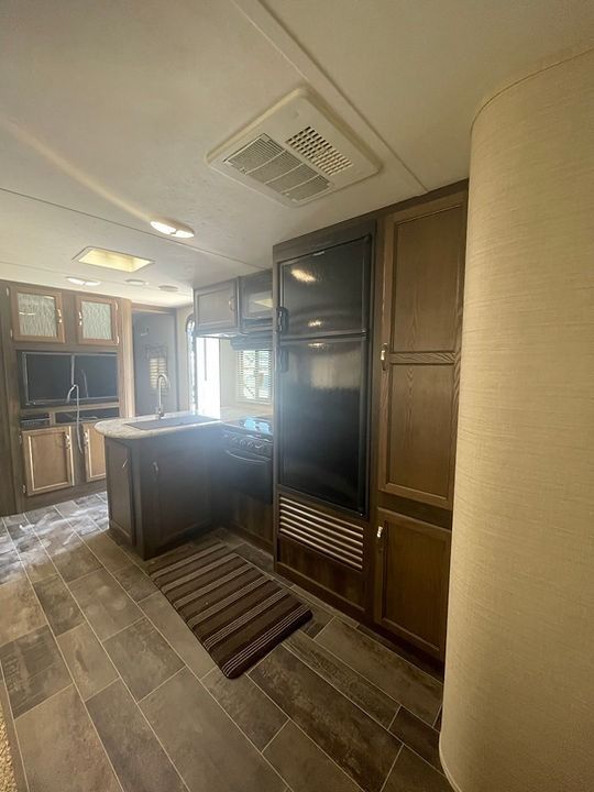 A kitchen with wooden cabinets and a flat screen tv.