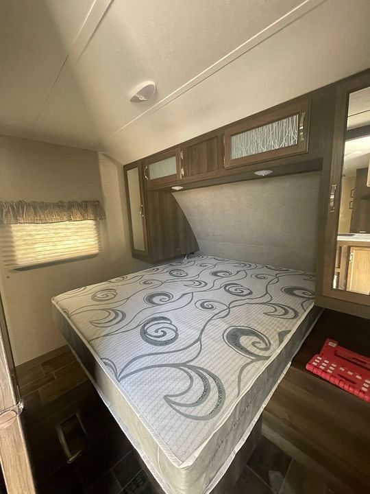 A mattress is sitting on top of a bed in a trailer.