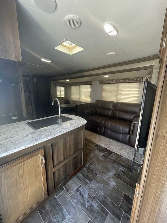 A living room with a couch , sink , and television.