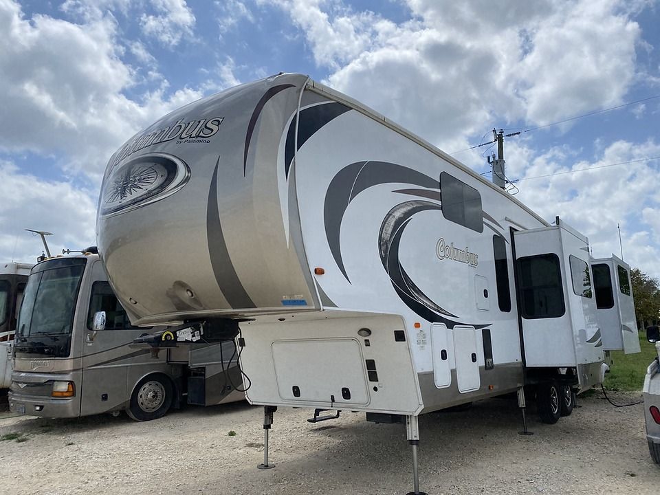 A white rv is parked next to another rv in a parking lot.