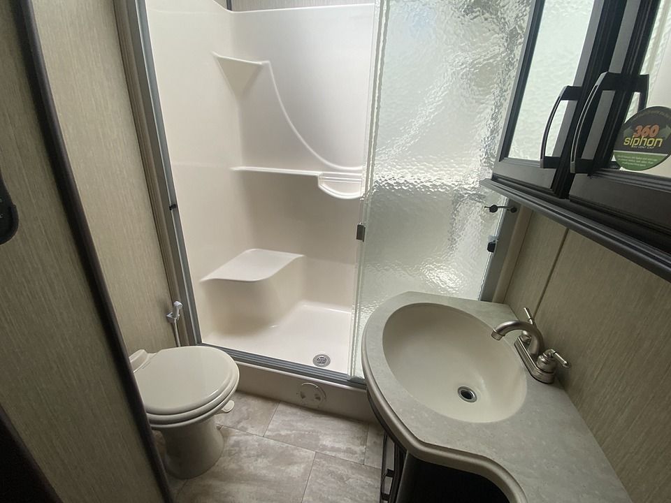 A bathroom with a toilet , sink and shower.