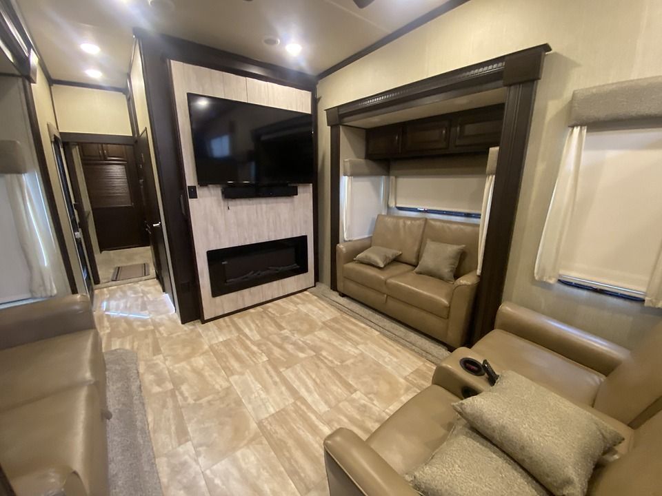 A living room with a couch , chair , television and fireplace.