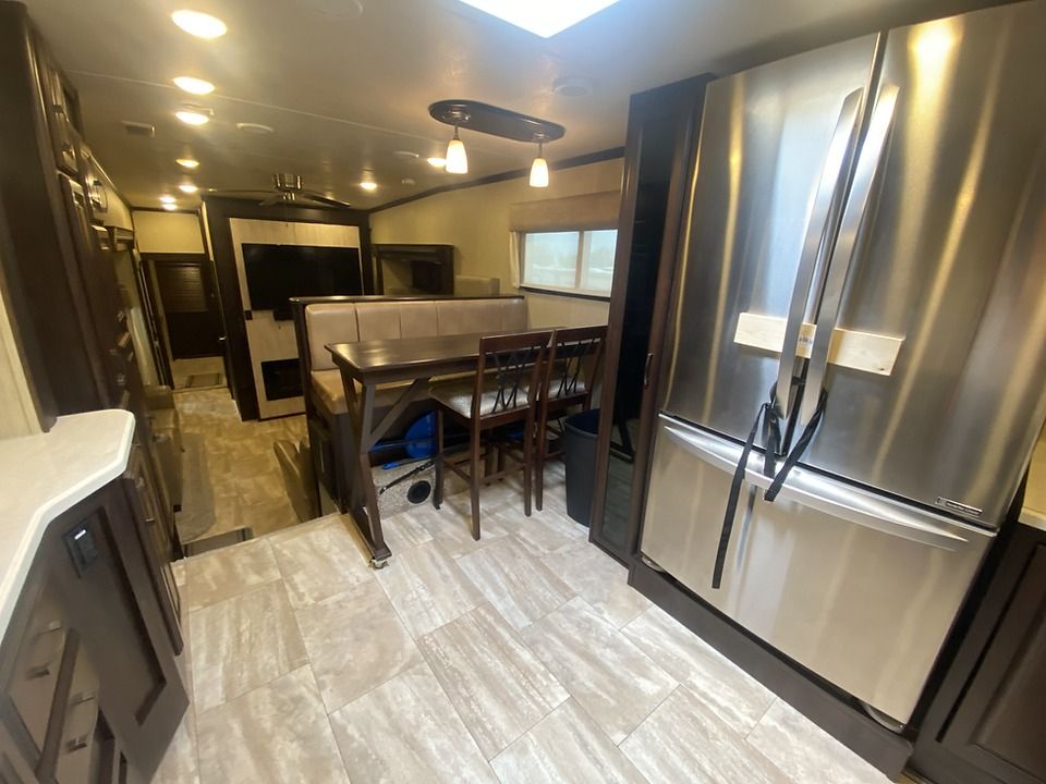 A kitchen with a stainless steel refrigerator and a table and chairs.