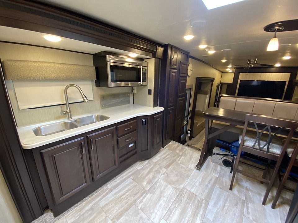 A kitchen with a sink , microwave , table and chairs.