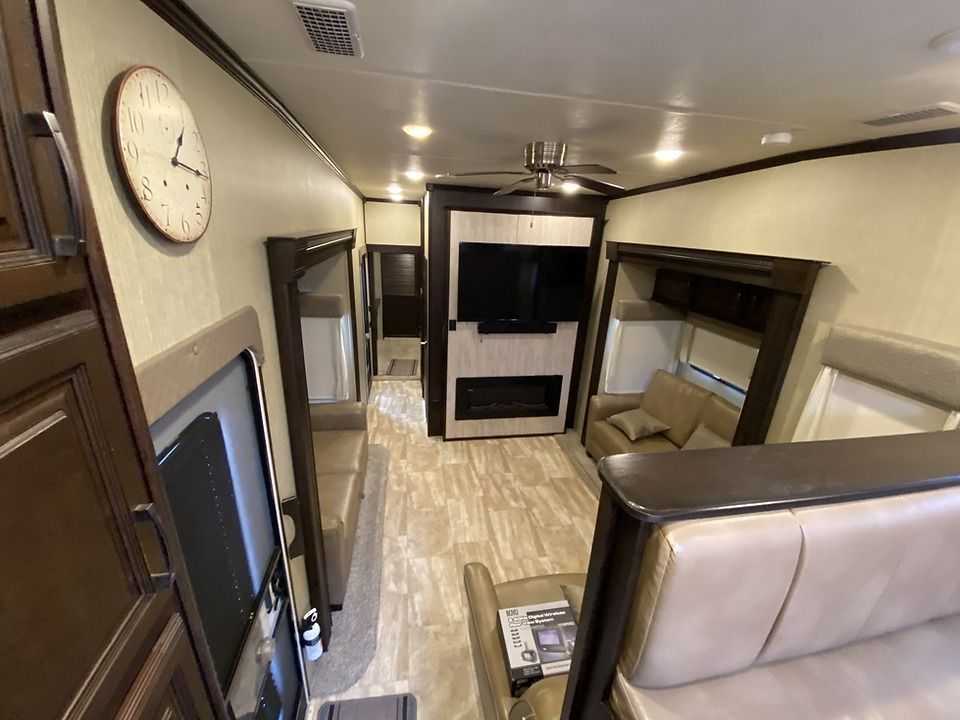 A living room in a rv with a clock on the wall.