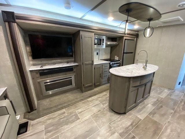 A kitchen with a large island and a flat screen tv.