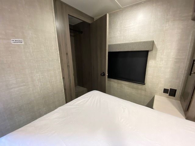 A bedroom with a bed and a television on the wall.