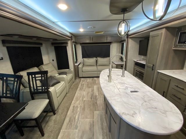 A living room with a couch and chairs and a kitchen with a large island.