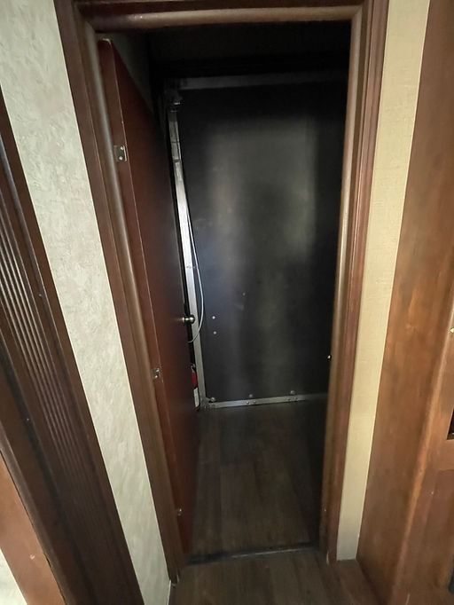 A door is open in a hallway with a wooden floor.